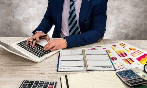 Businessman working in office with business graphs, laptop and notepad Businessman working in office with business graphs, laptop and notepad.