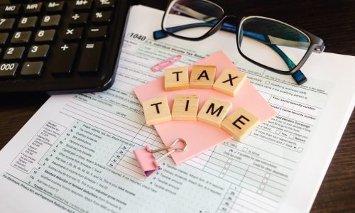 tax forms with glasses and calculator. Tax Time - wooden letters, tax form with sticker, glasses and calculator.