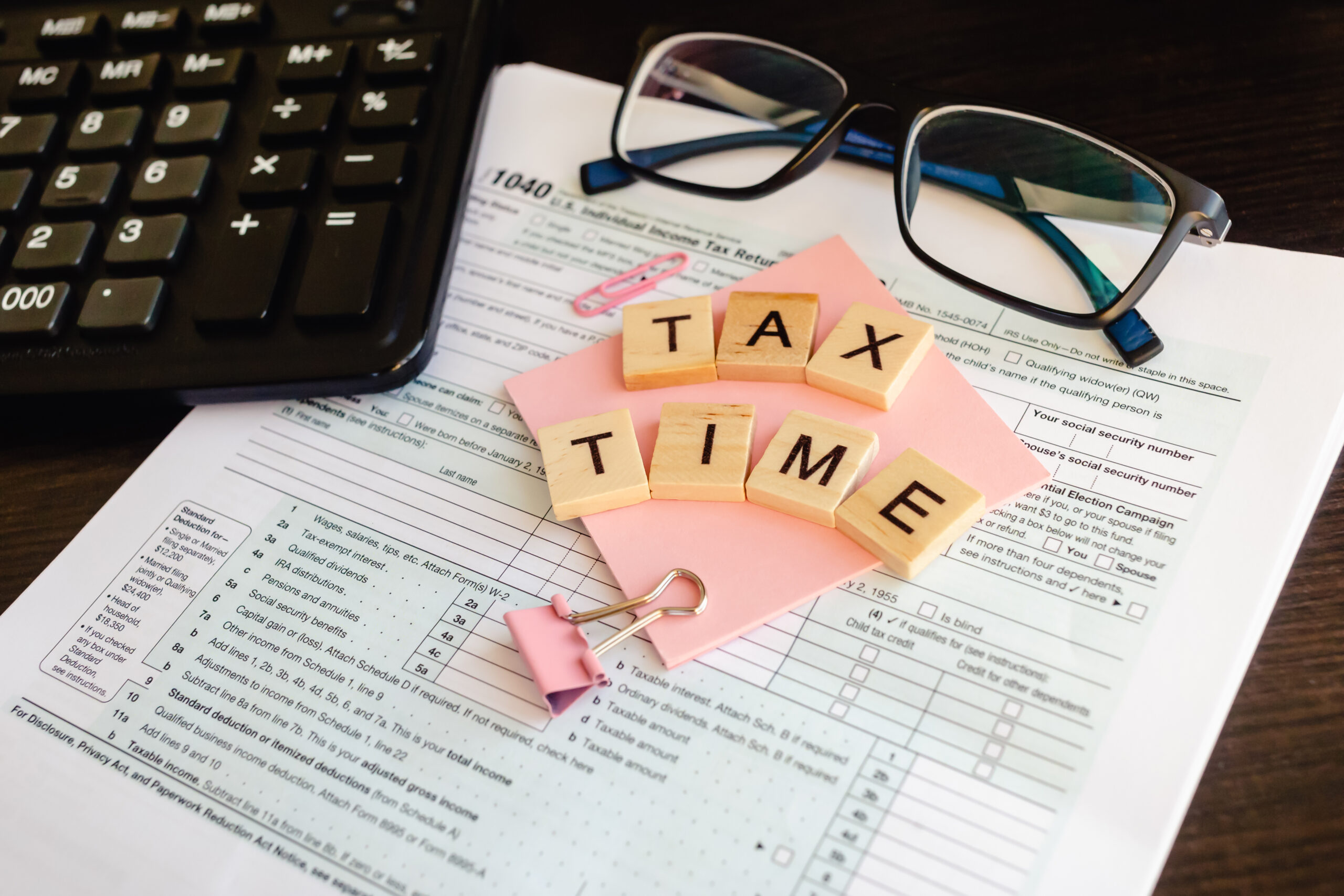 tax forms with glasses and calculator. Tax Time - wooden letters, tax form with sticker, glasses and calculator.
