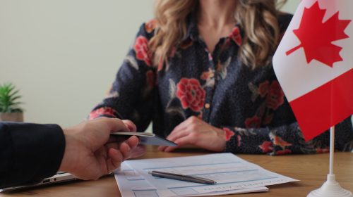 Canadian woman consular officer giving passport to male immigrant, work visa, citizenship. Visa Application online form immigration concept. Visa approval